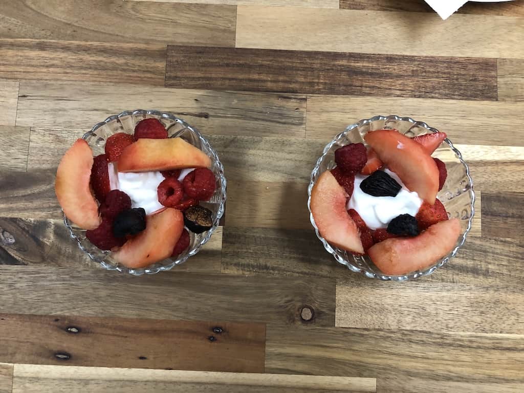 starter of Sliced plums, raspberries, strawberries, and figs over Greek yogurt